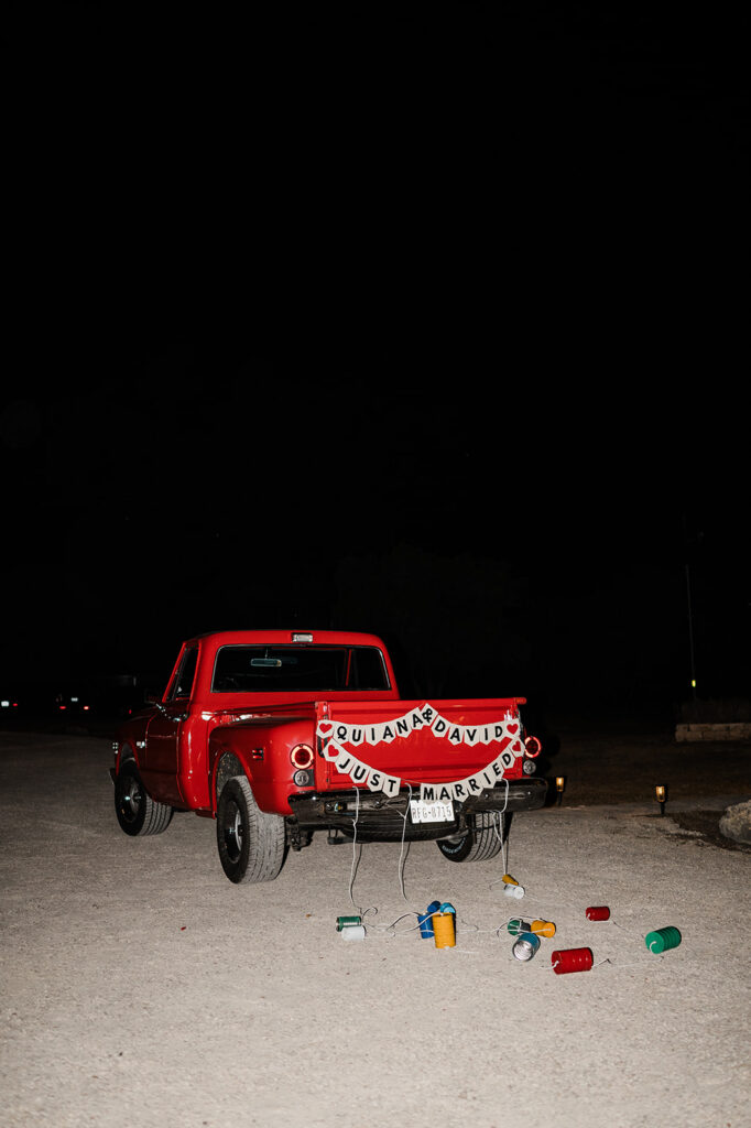 Quiana and David's send-off in a vintage red truck at Jacob's Well Vineyard in Wimberley, TX