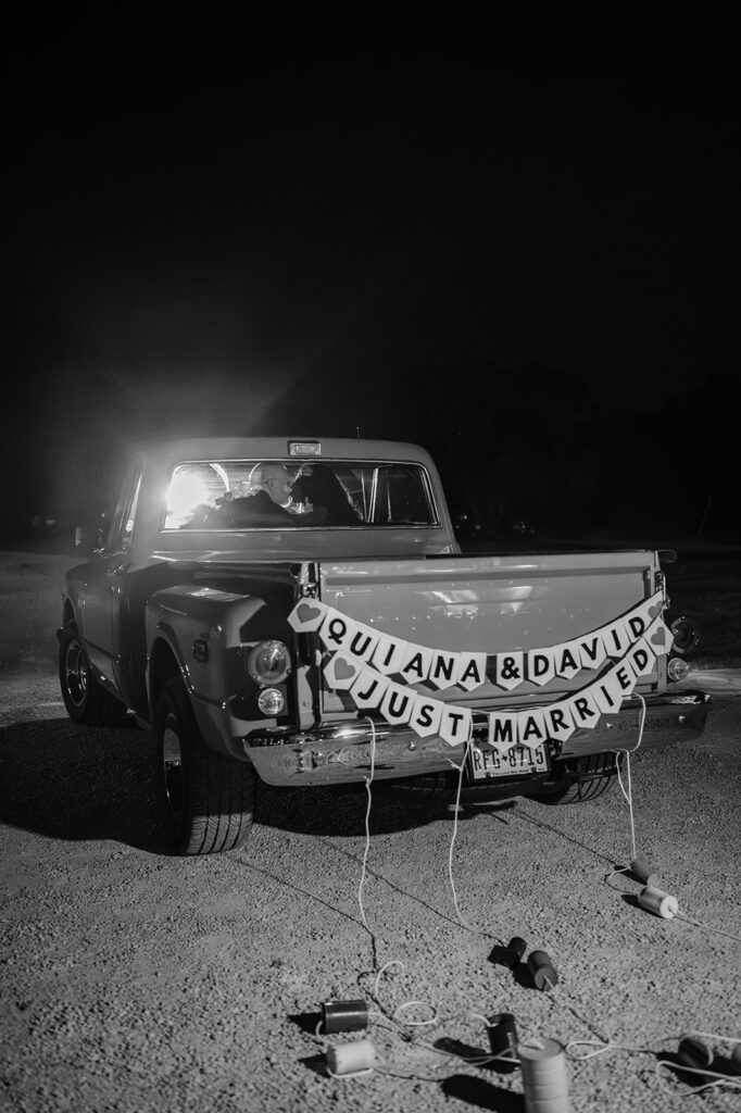 Quiana and David's send-off in a vintage red truck at Jacob's Well Vineyard in Wimberley, TX
