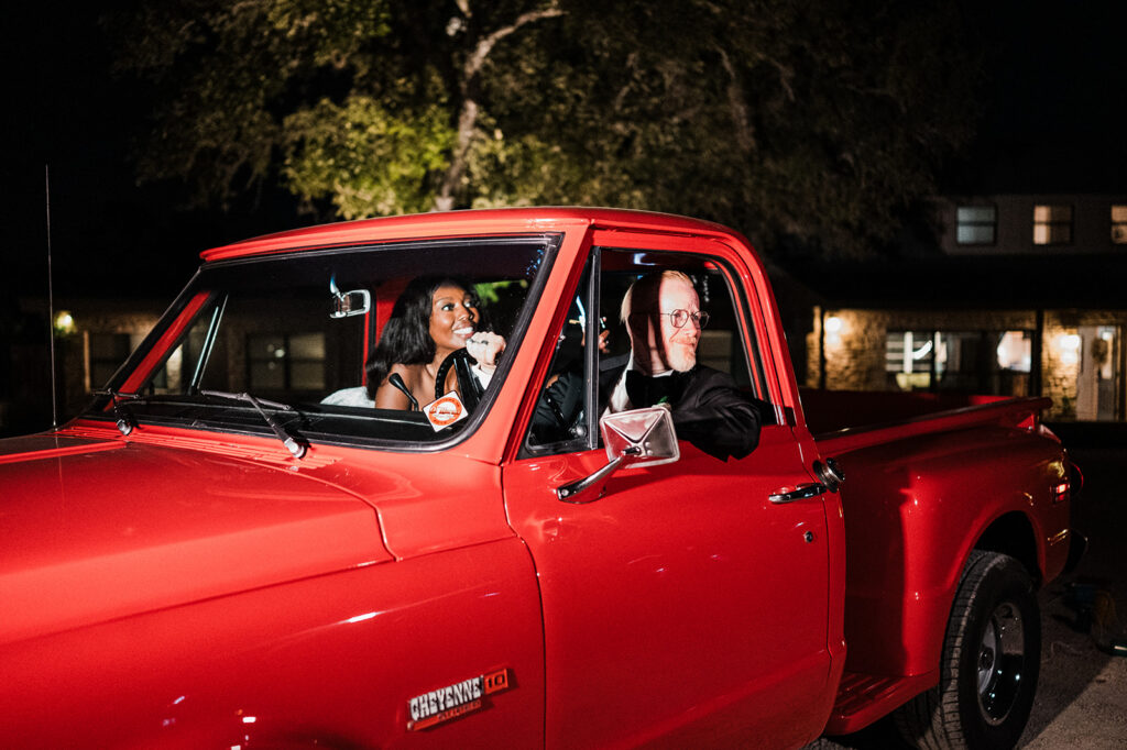 Quiana and David's send-off in a vintage red truck at Jacob's Well Vineyard in Wimberley, TX
